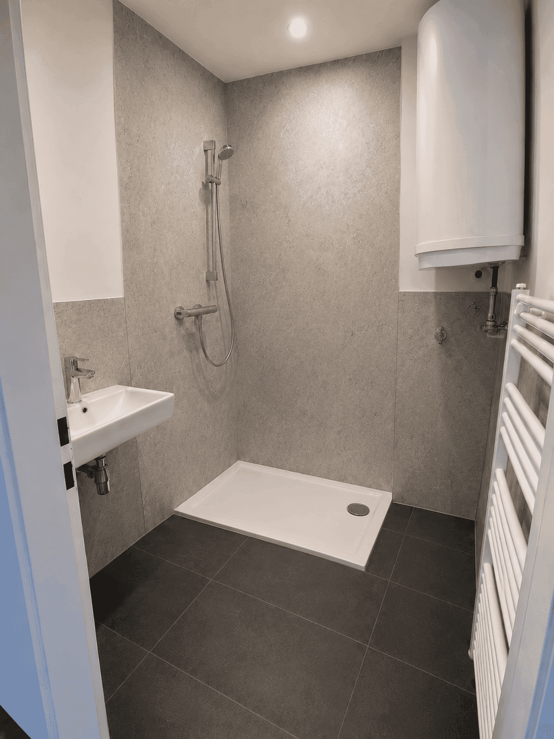 Modernes Badezimmer mit grauen Fliesen, Dusche und beheiztem Handtuchhalter.