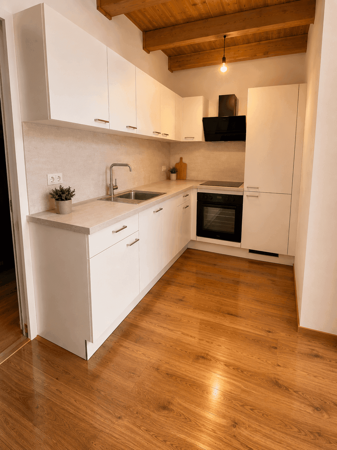 Moderne Einbauküche mit weißen Schränken, Holzdecke und sichtbaren Holzbalken.