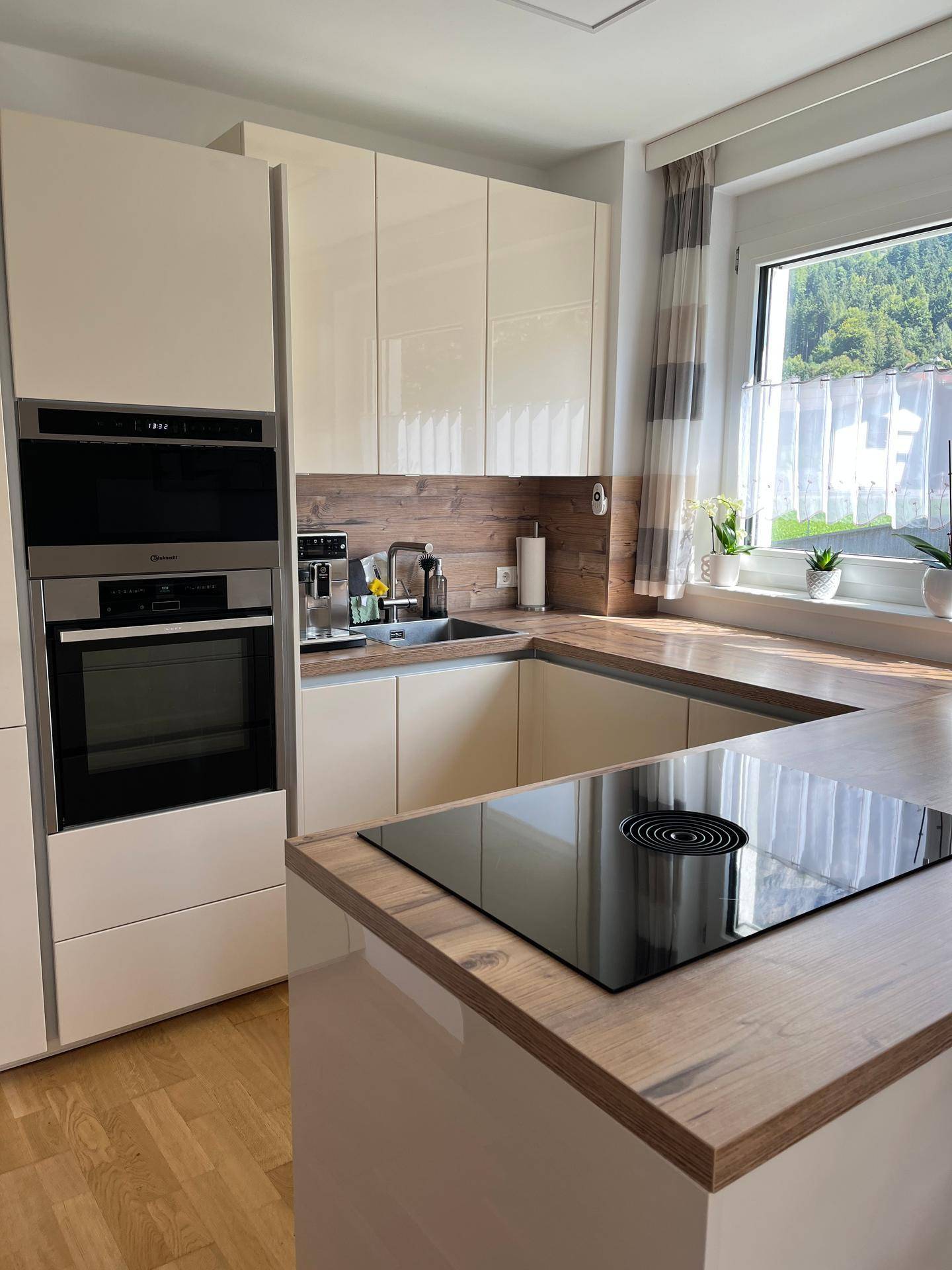 Moderne Einbauküche mit glänzenden Fronten, Induktionskochfeld und integrierten Geräten.