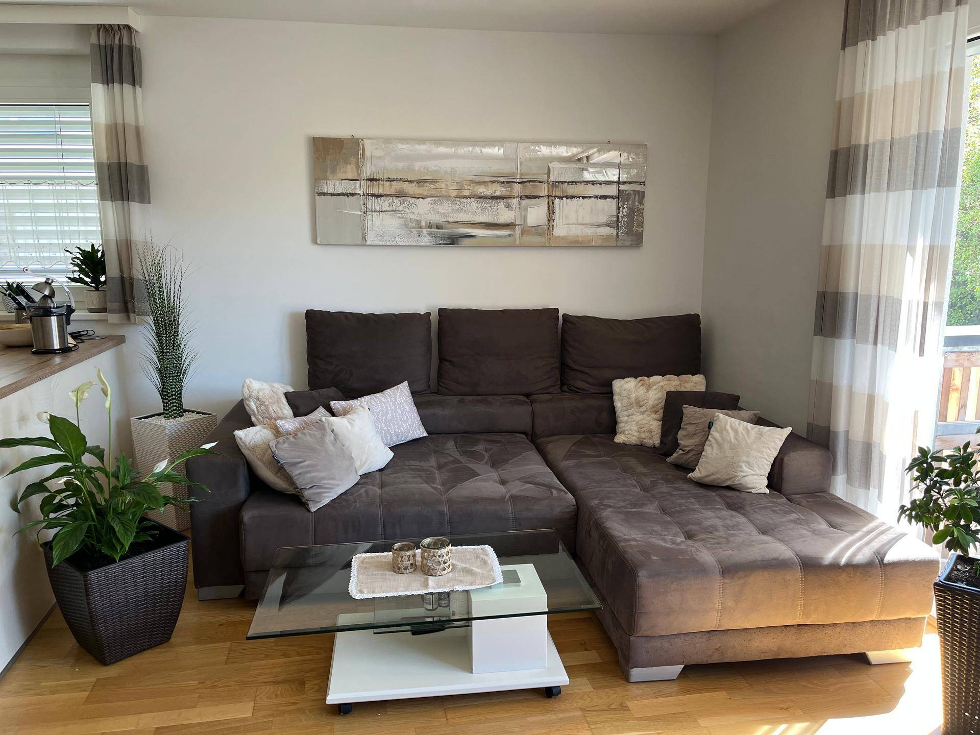 Heller Wohnbereich mit großem Ecksofa, Couchtisch und moderner Kunst an der Wand.