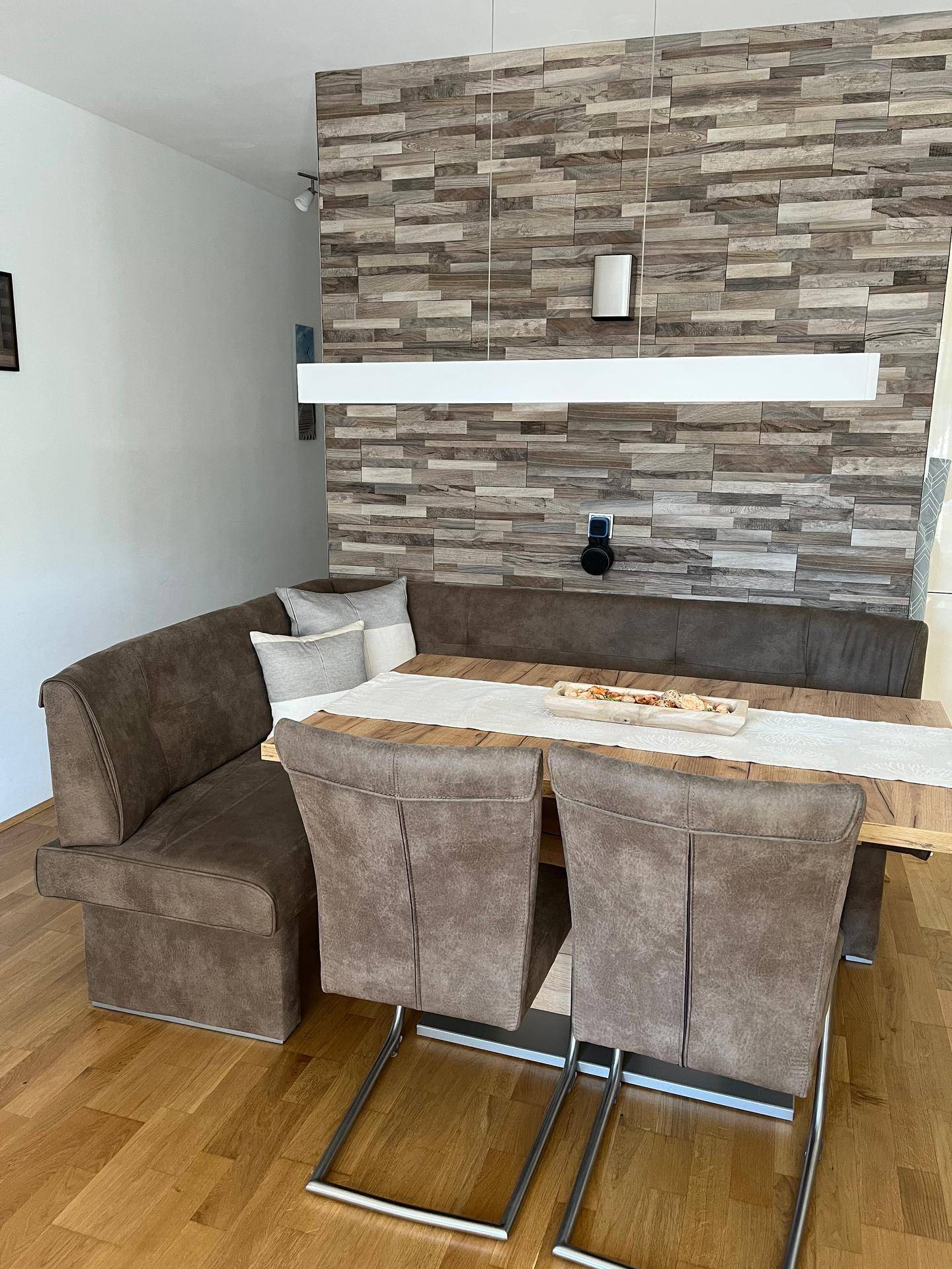 Gemütlicher Essbereich mit Eckbank, Holztisch und moderner Wandverkleidung.