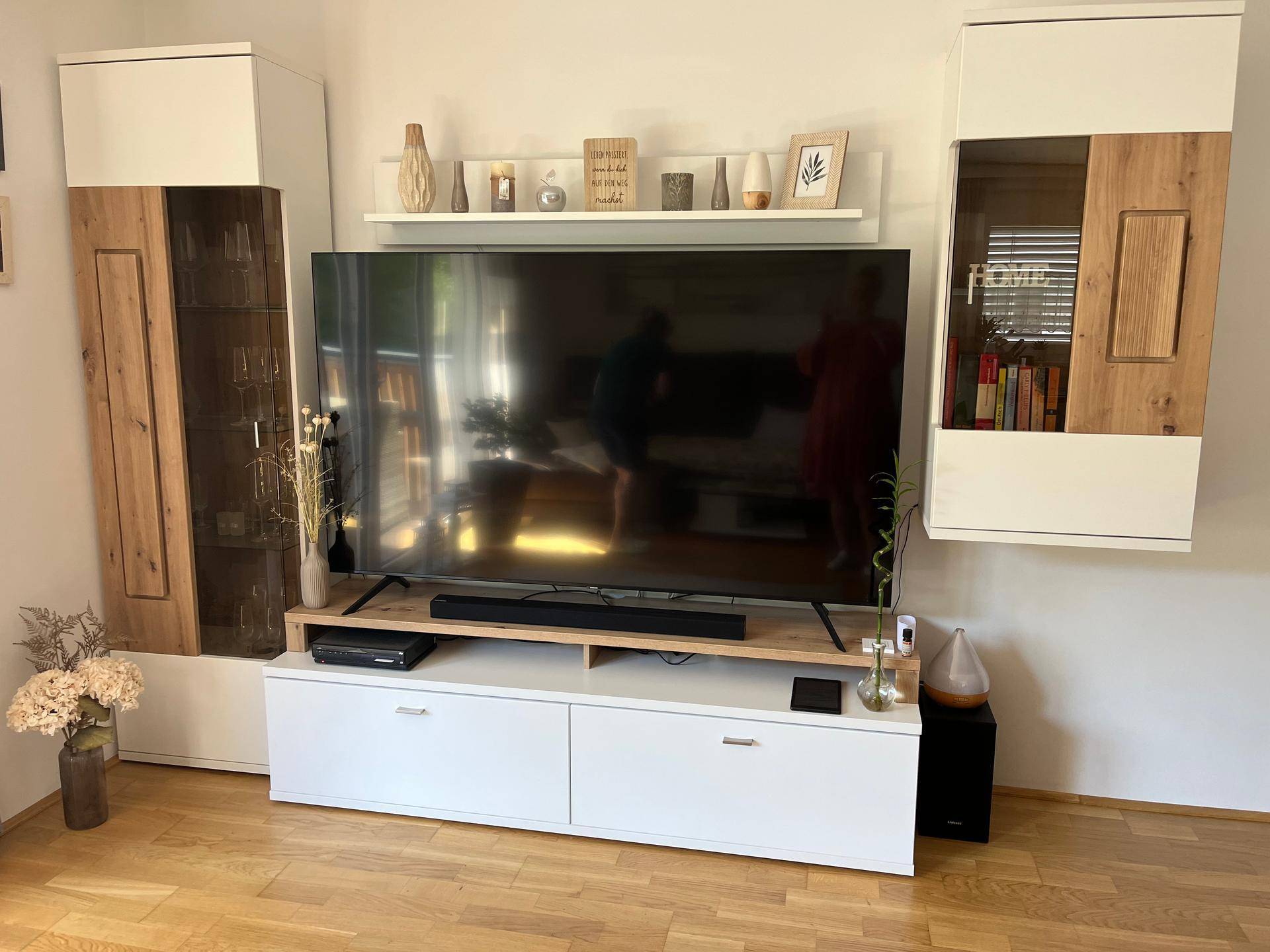 Wohnzimmer mit großem Flachbildfernseher und modernen Wandregalen und Schränken.