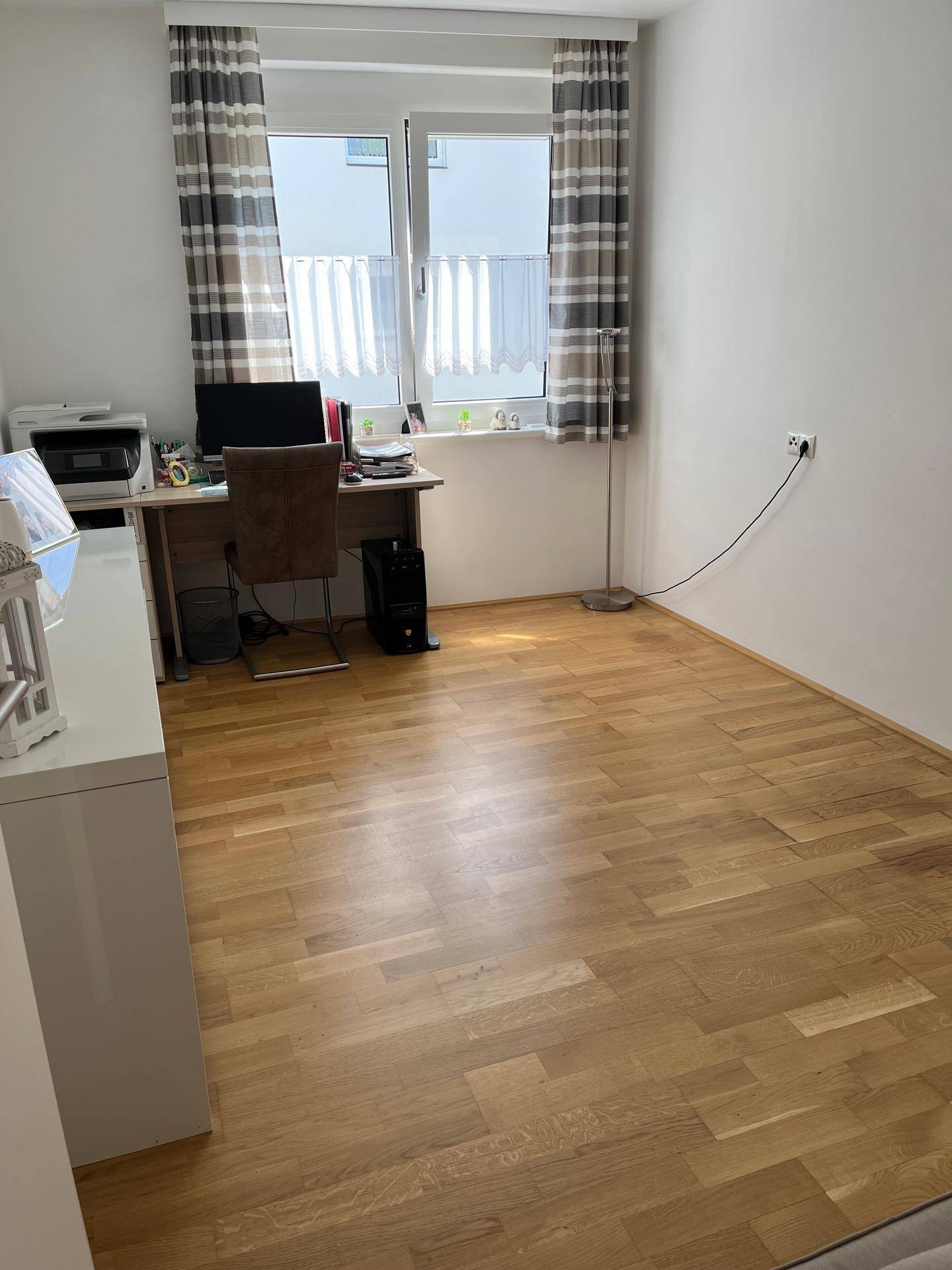 Helles Arbeitszimmer mit Schreibtisch, Bürostuhl und Holzboden.