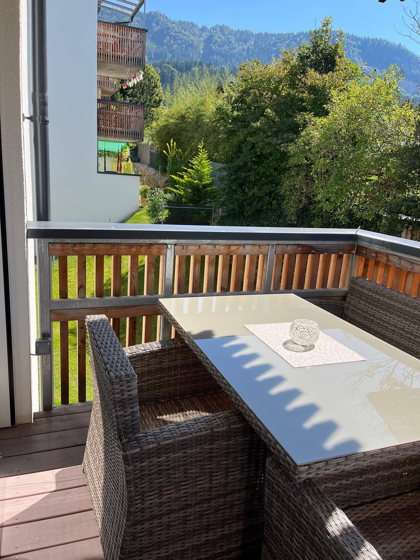 Sonniger Balkon mit Rattanmöbeln und herrlichem Blick auf die umliegenden Berge.