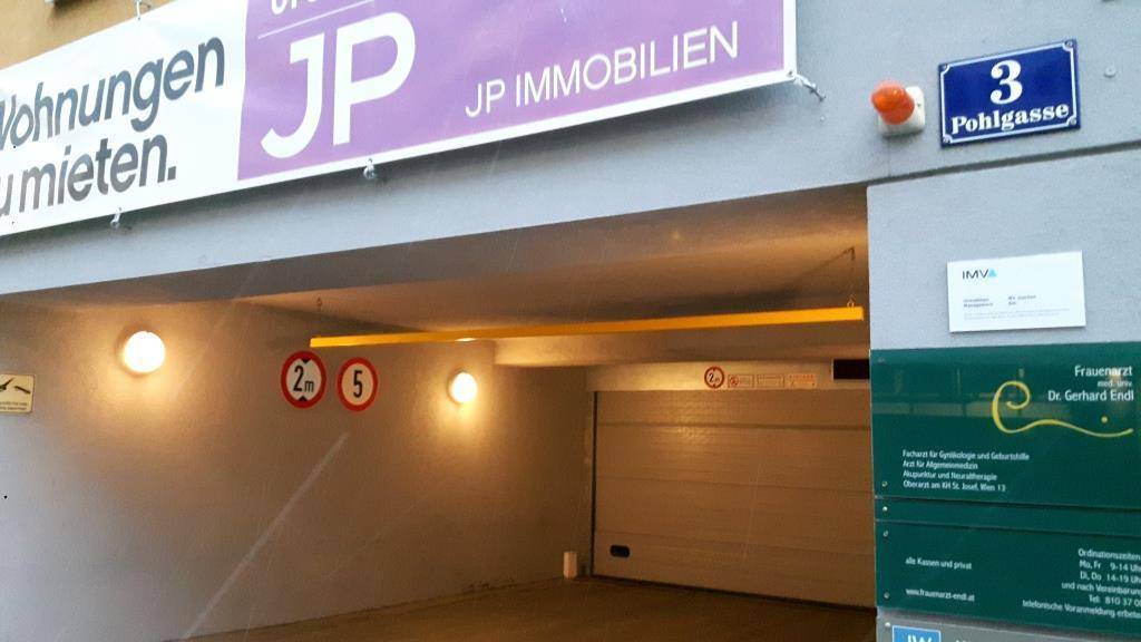 Eingangsbereich einer Tiefgarage mit Höhenbegrenzung und Rolltor.