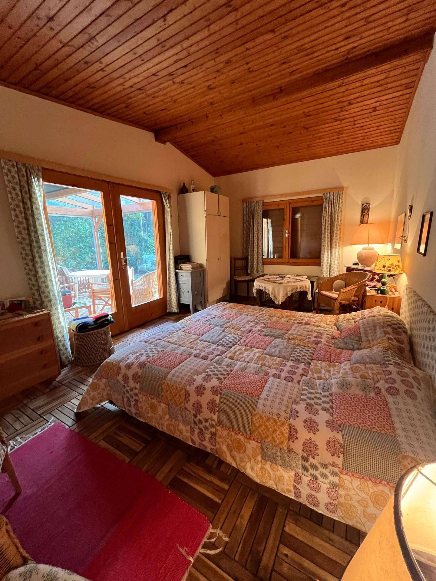 Helles Schlafzimmer mit Holzboden und direktem Zugang zur überdachten Terrasse.