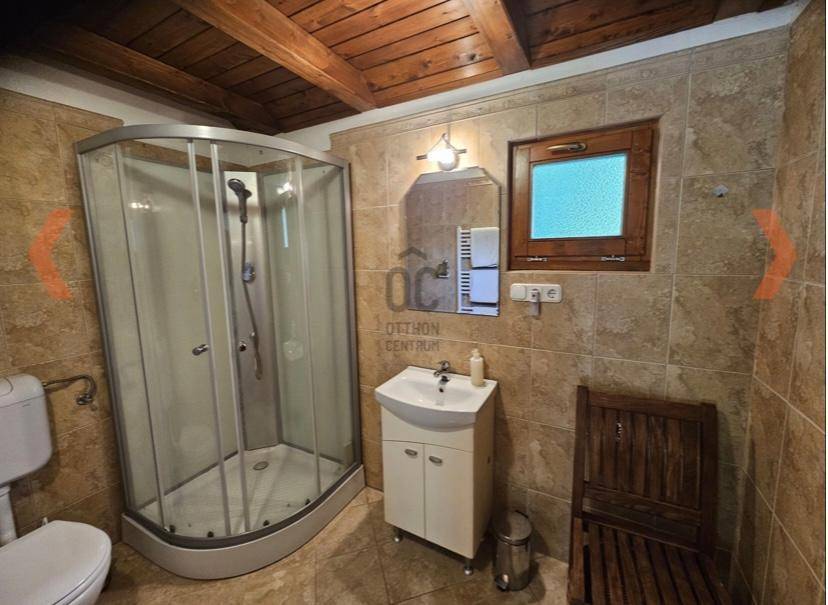 Funktionales Badezimmer mit Duschkabine, Einzelwaschbecken und hellen Fliesen an Wänden und Boden.