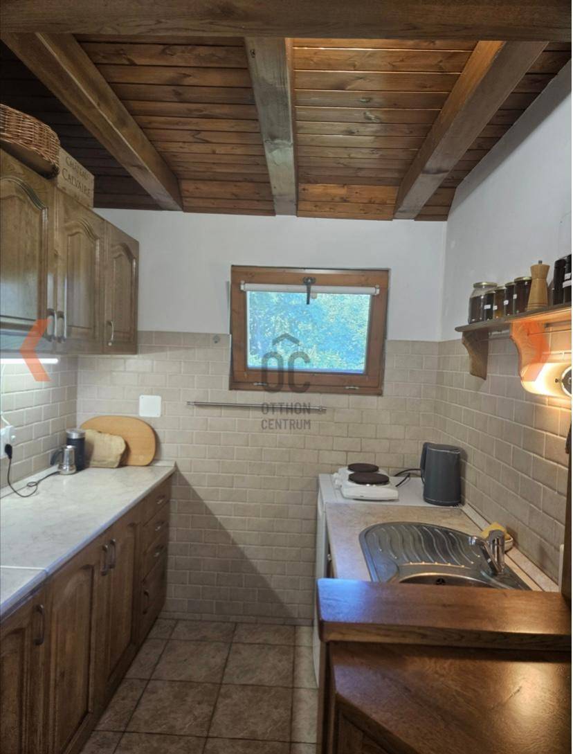 Funktionale Küche mit Holzschränken, Fliesenrückwand und einem Fenster mit Blick ins Grüne.