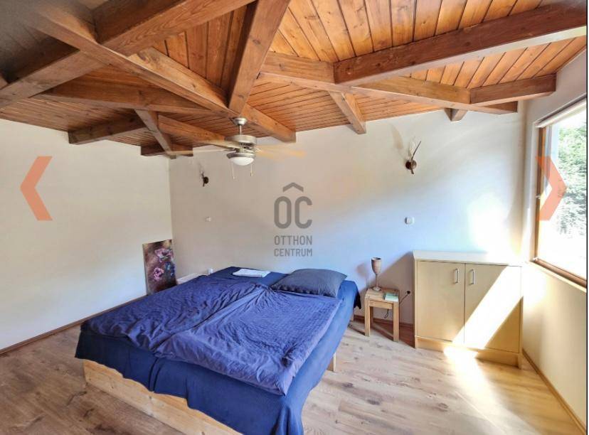 Gemütliches Schlafzimmer mit Doppelbett, Holzbalkendecke und Deckenventilator für Komfort.