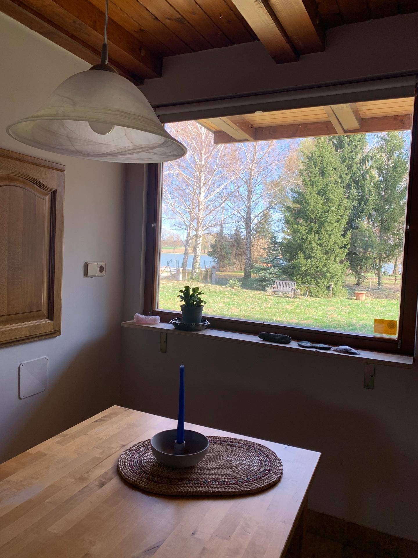 Heller Essbereich mit Holztisch und weitem Blick auf den See und die umliegende Natur.