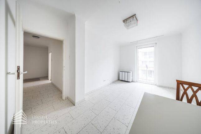 Heller Wohnbereich mit Fliesenboden, einem Esstisch und Zugang zu einem Balkon.