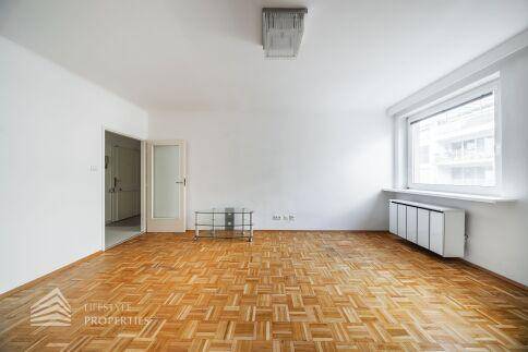 Geräumiges Wohnzimmer mit Parkettboden, viel Tageslicht und Zugang zu weiteren Räumen.