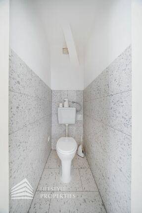 Kleines Gäste-WC mit hellen Fliesen an Wänden und Boden.