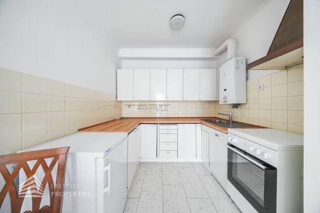 Funktionale Küche mit weißen Schränken, Holz-Arbeitsplatten und integrierten Geräten.