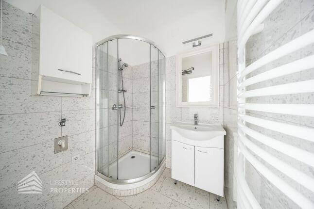 Modernes Badezimmer mit Duschkabine, Waschbecken und beheiztem Handtuchhalter.