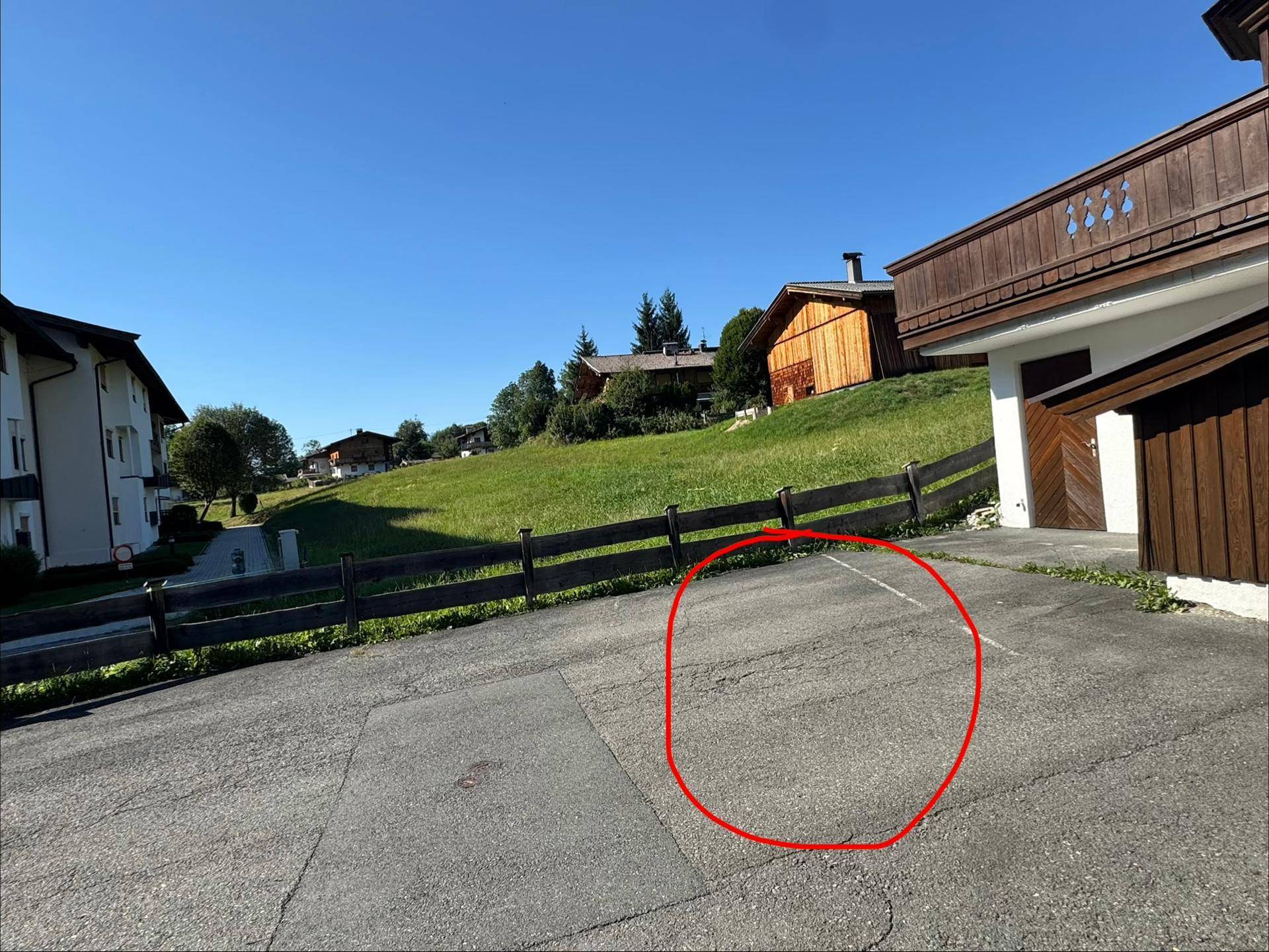 Außenparkplatz auf einer asphaltierten Fläche vor dem Gebäude mit umliegender Natur.