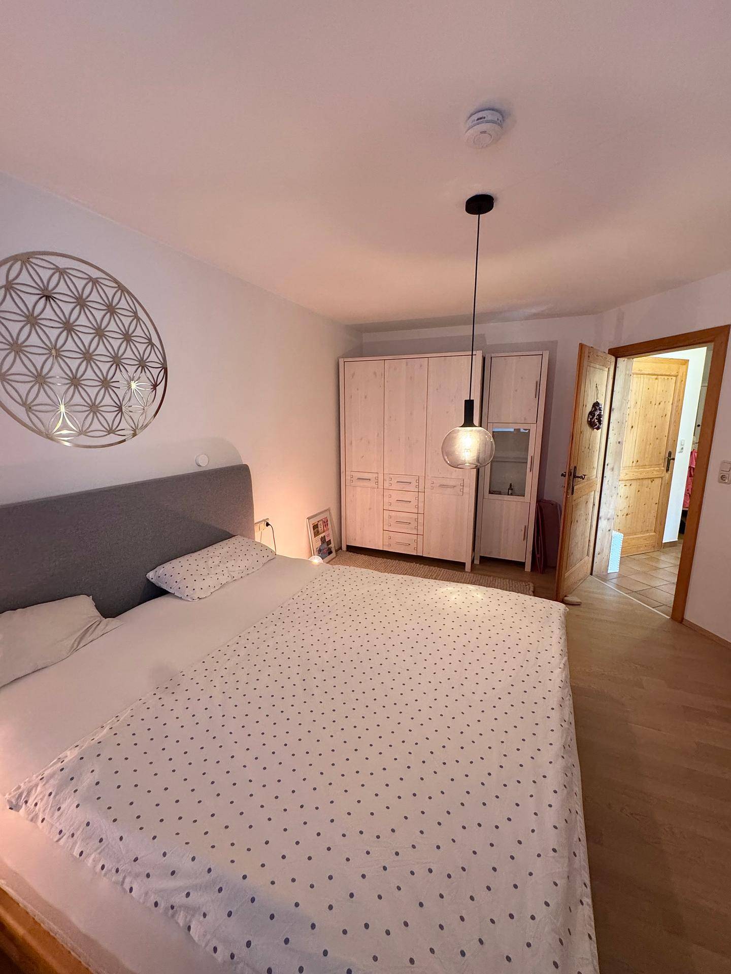 Schlafzimmer mit hellem Holzboden, Kleiderschrank und Zugang zu weiteren Räumen.