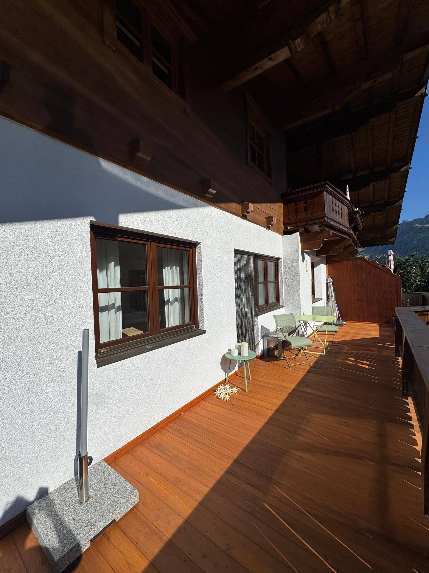 Langer Holzbalkon mit traditionellen Elementen und Platz für kleine Sitzgelegenheiten im Freien.