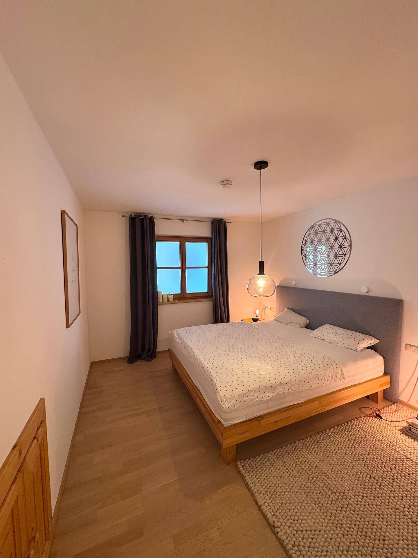 Schlafzimmer mit Holzboden, einem bequemen Bett und einem Fenster für natürliches Licht.