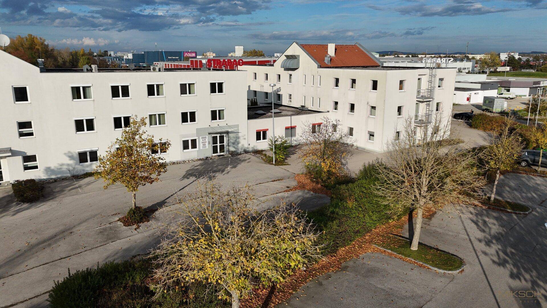 Luftaufnahme des Geschäftskomplexes mit mehreren Gebäuden und ausgedehnten Parkflächen.