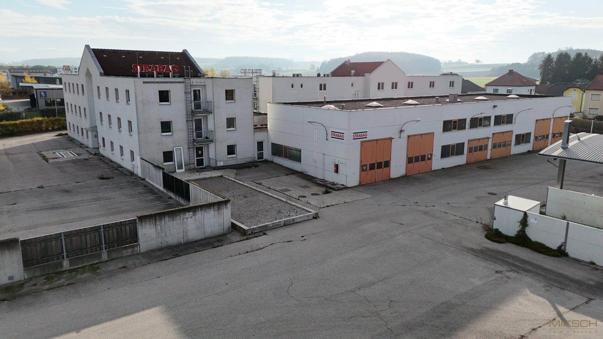 Luftaufnahme des Geschäftskomplexes mit einem Hauptgebäude und einer angrenzenden Halle.