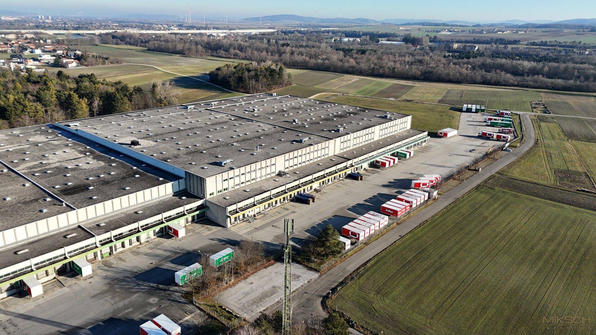 Luftaufnahme der langen Fassade des Lagergebäudes mit zahlreichen Laderampen und Freiflächen für LKWs.
