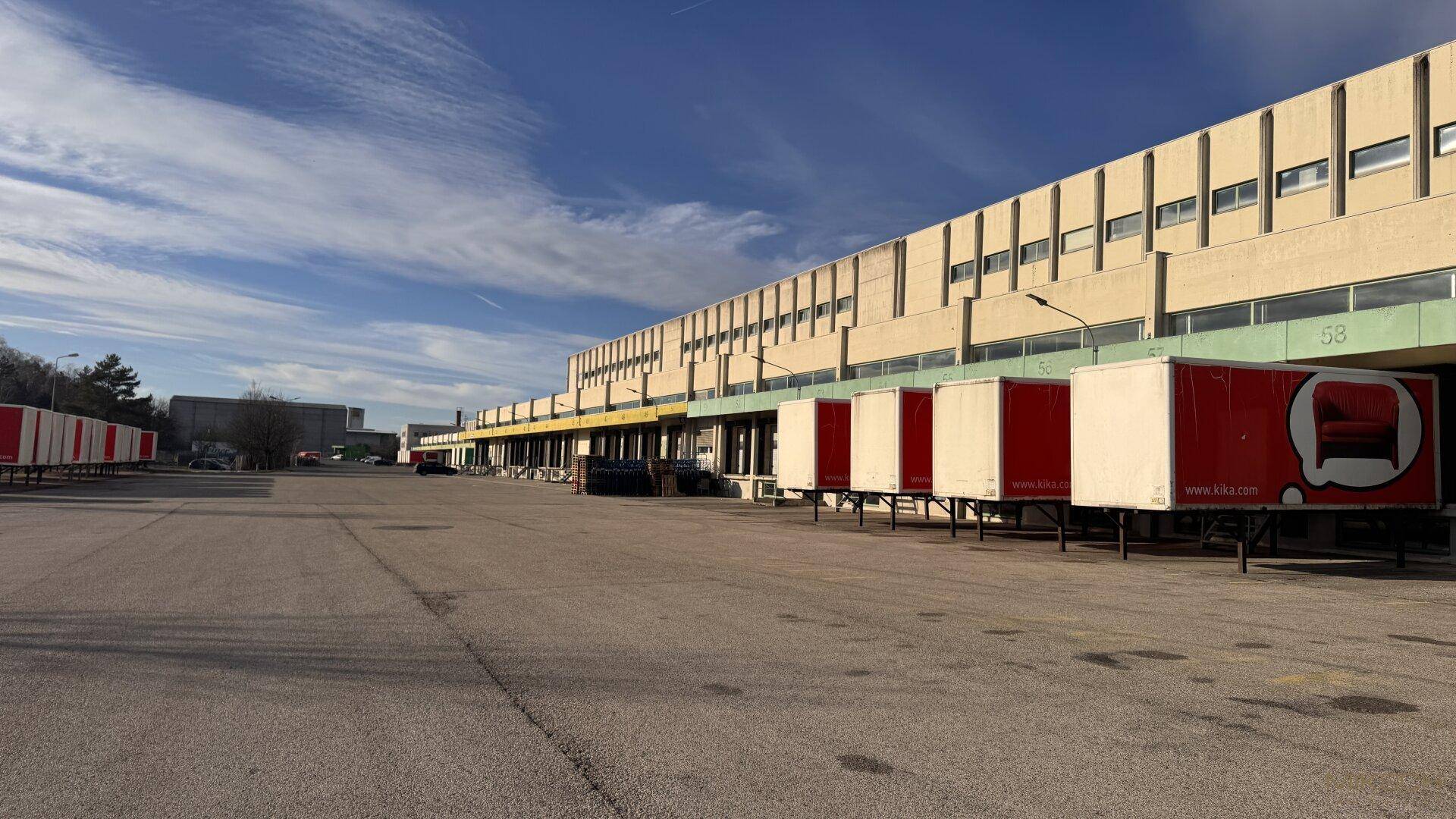 Weitläufiger Vorplatz vor den Laderampen eines großen Logistikzentrums mit abgestellten Anhängern.
