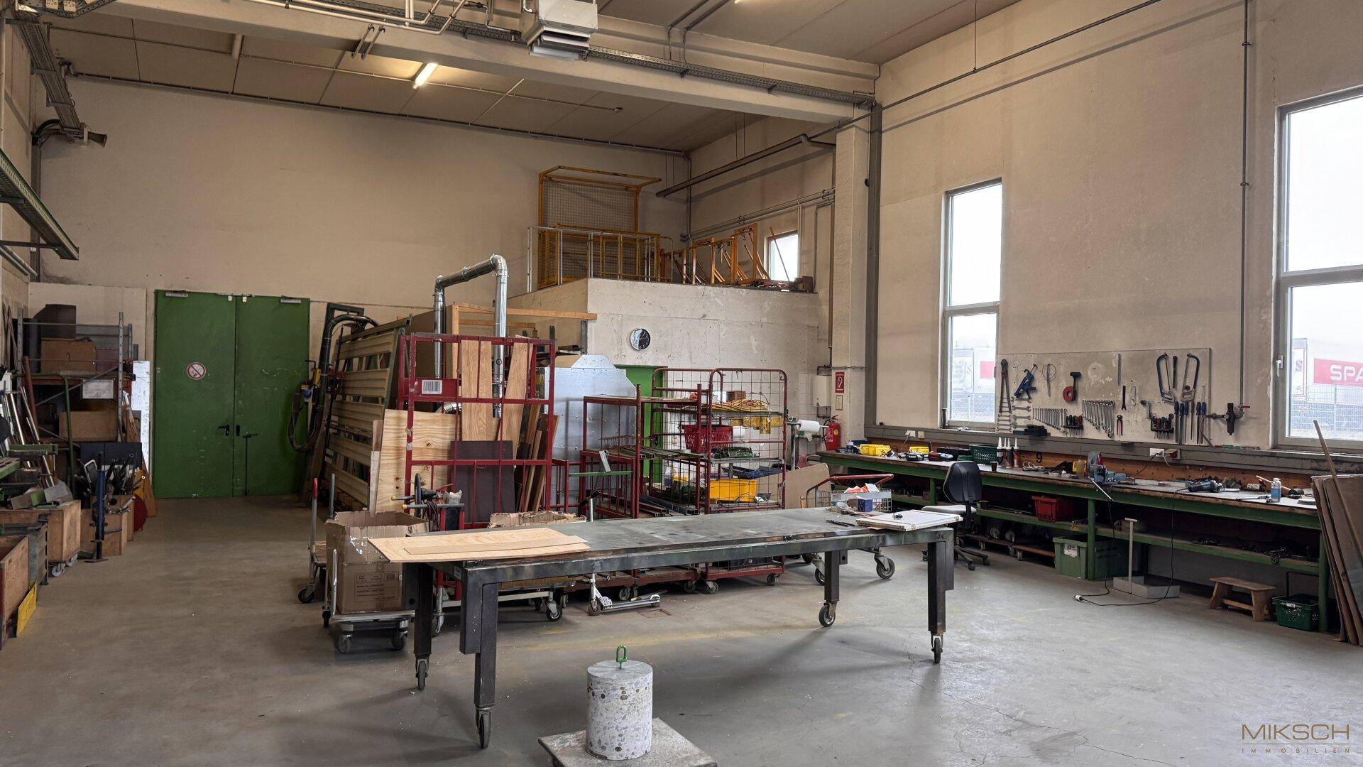 Großer Werkstattraum mit industriellem Charme, hohen Decken und viel Platz für verschiedene Tätigkeiten.
