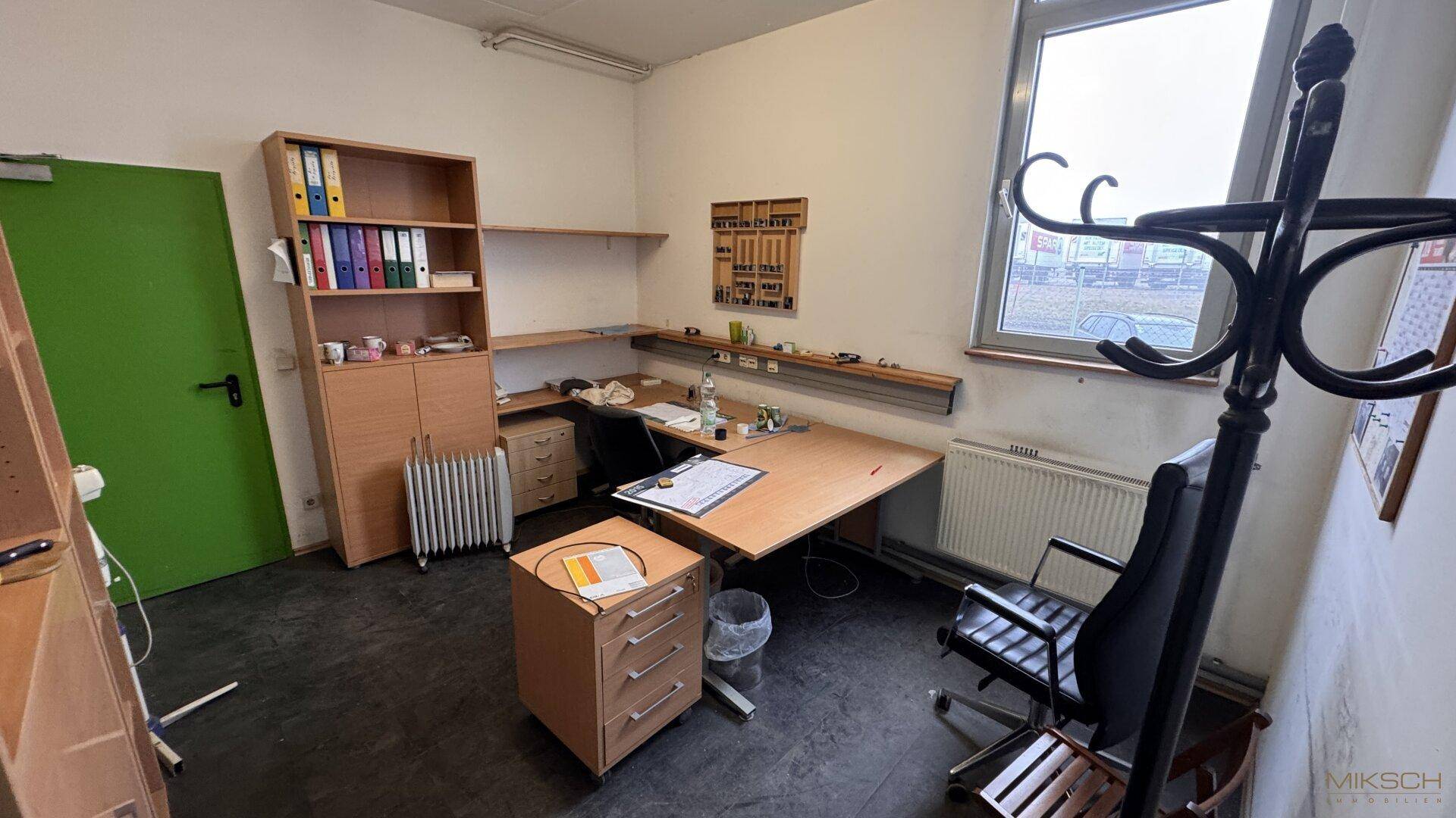 Geräumiges Büro mit Holzmöbeln, Schreibtisch und einem Fenster, das Tageslicht hereinlässt.
