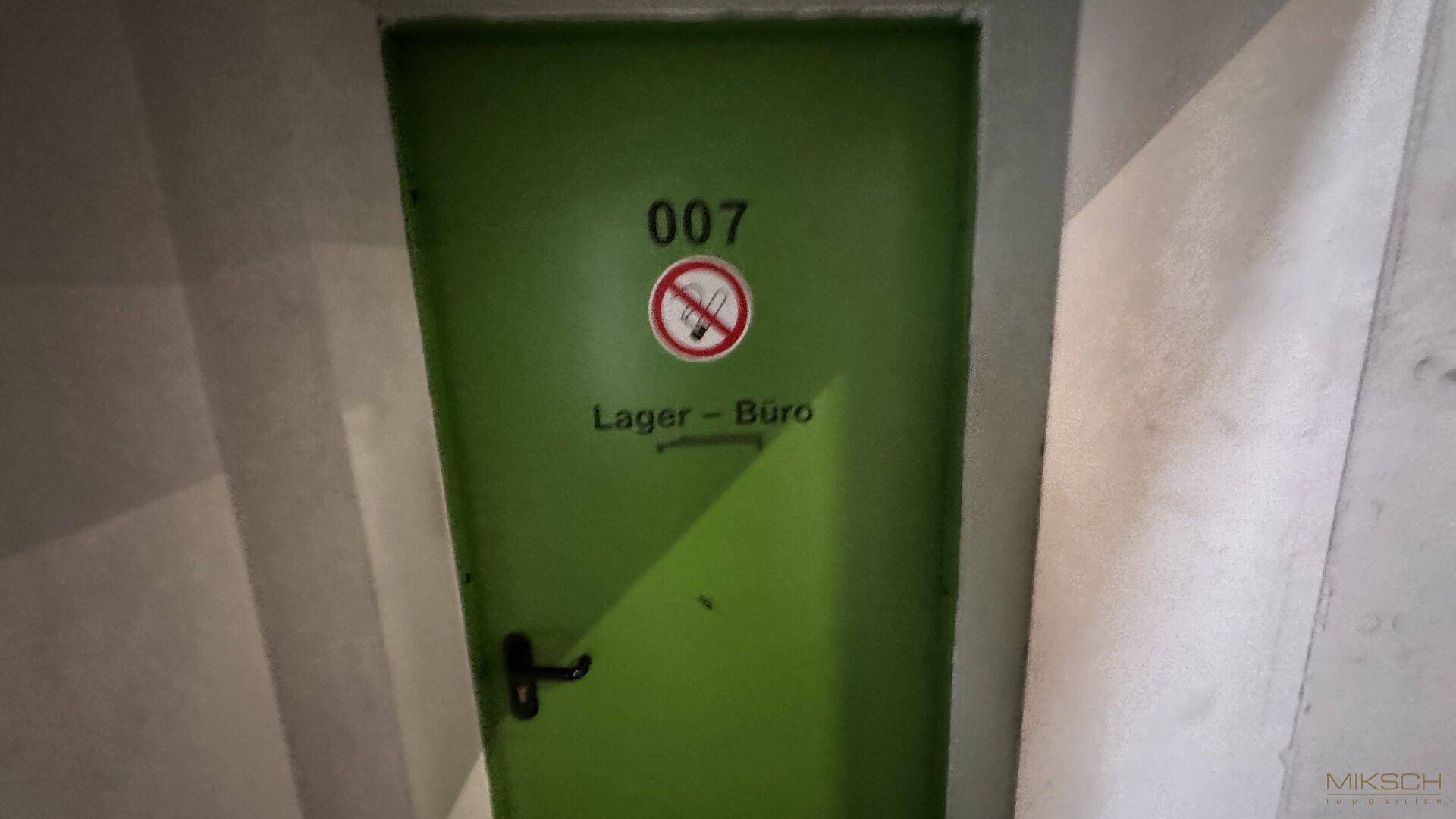 Grüne Tür mit der Nummer 007 und Beschriftung "Lager - Büro", die zu einem Innenraum führt.