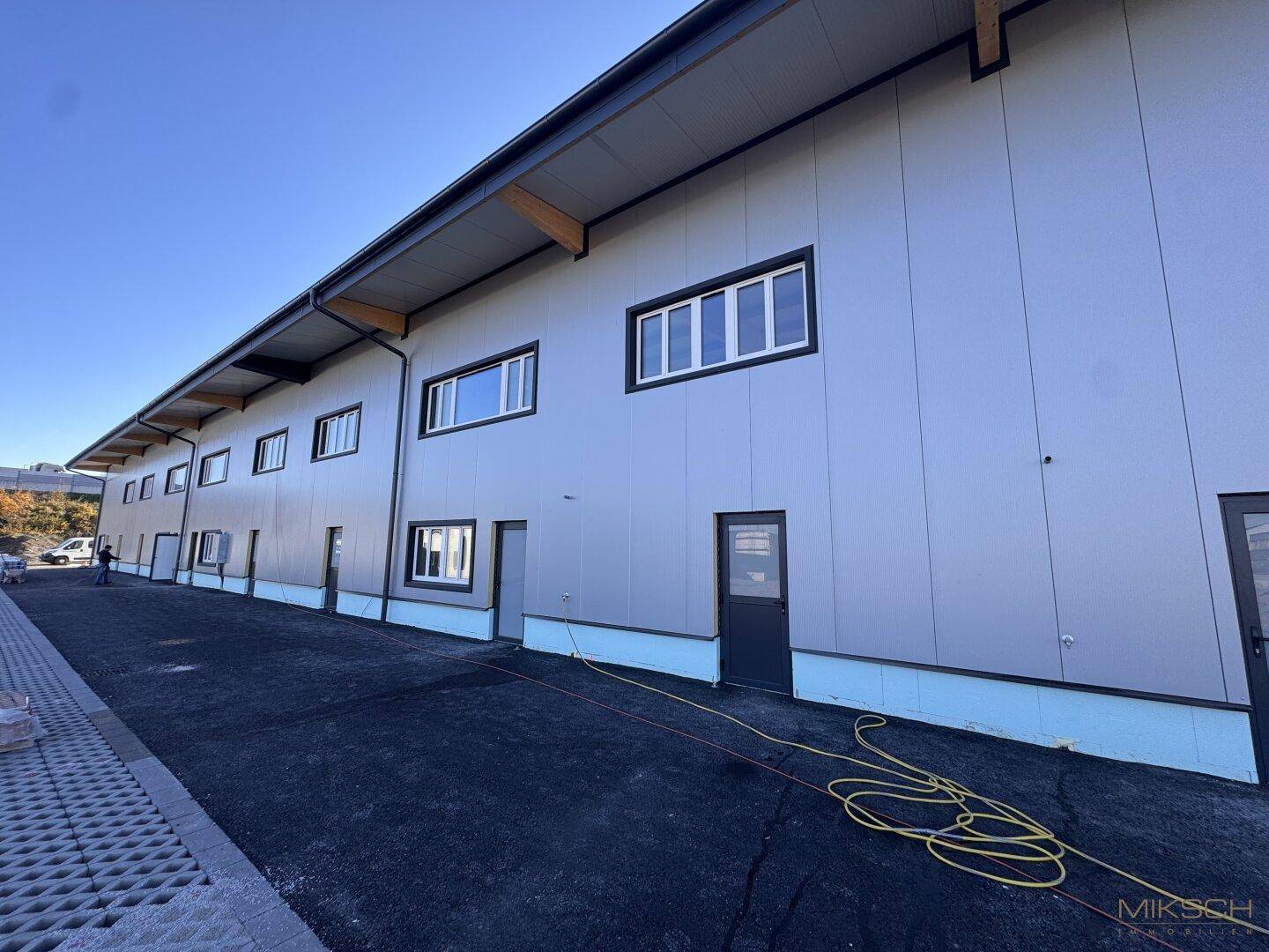 Seitenansicht des modernen Gebäudes mit mehreren Fenstern und Türen entlang der grauen Fassade.