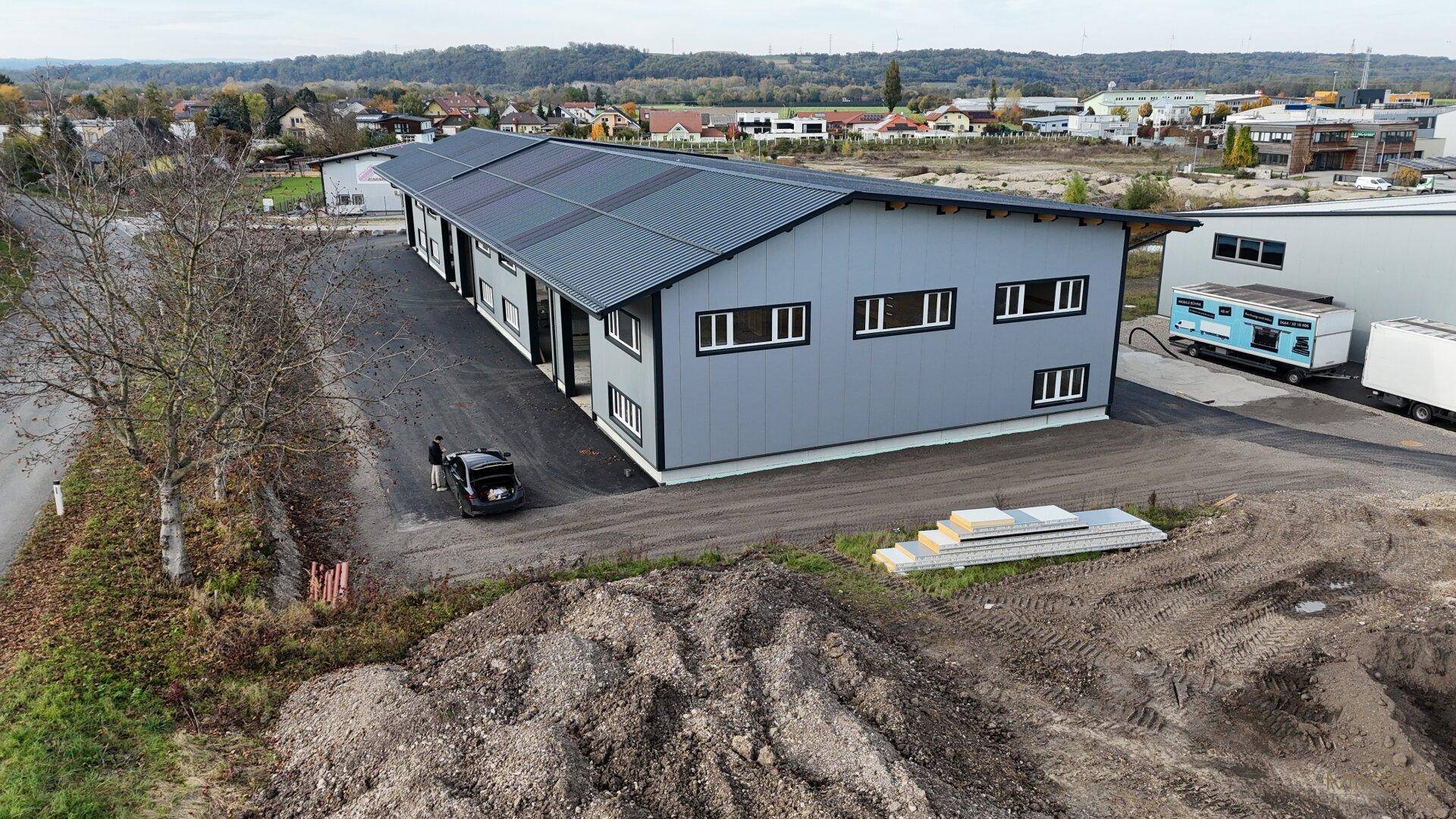 Luftaufnahme einer neu errichteten Gewerbehalle mit umliegendem Gelände und Blick auf die Umgebung.