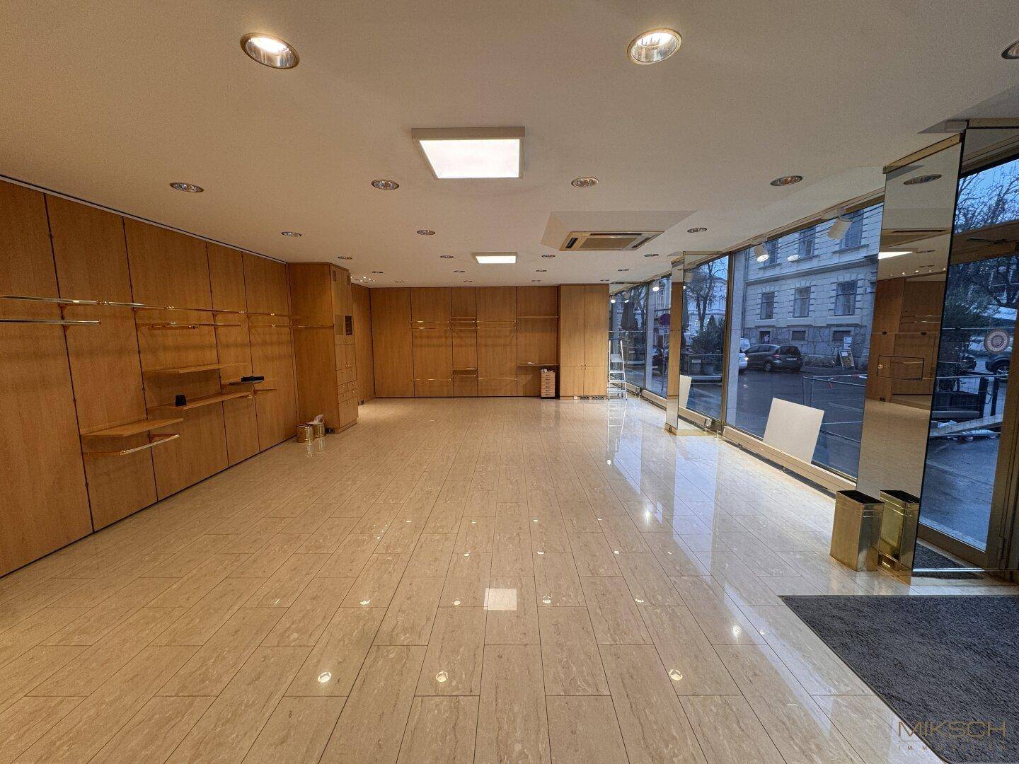 Heller und offener Gewerberaum mit großen Fensterfronten und eleganten Fliesenböden, bereit für neue Nutzung.