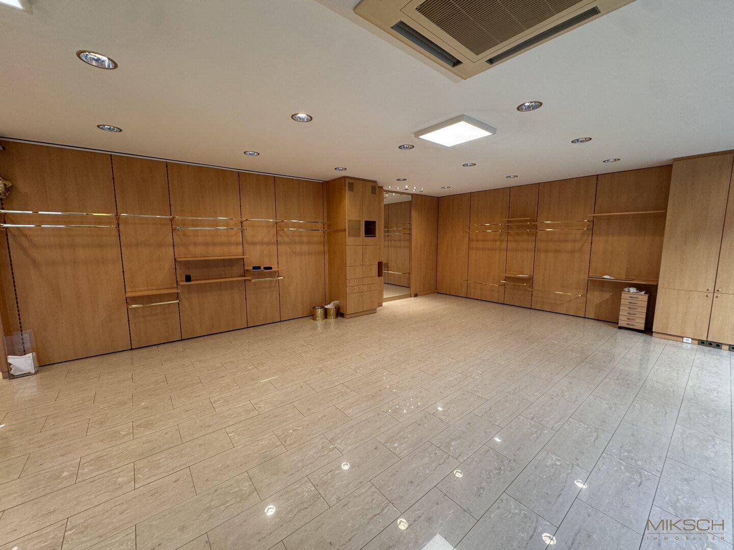 Weitläufiger Gewerberaum mit durchgehender Holzvertäfelung und glänzenden Fliesen, bietet vielseitige Gestaltungsmöglichkeiten.