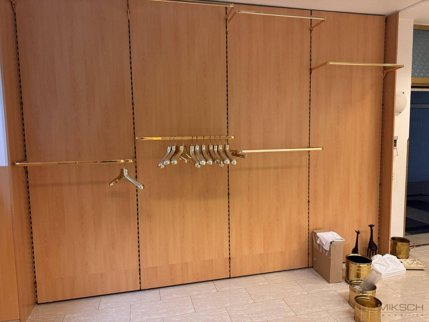 Detailansicht der Holzvertäfelung mit integrierten Kleiderstangen und Regalen im Gewerberaum.