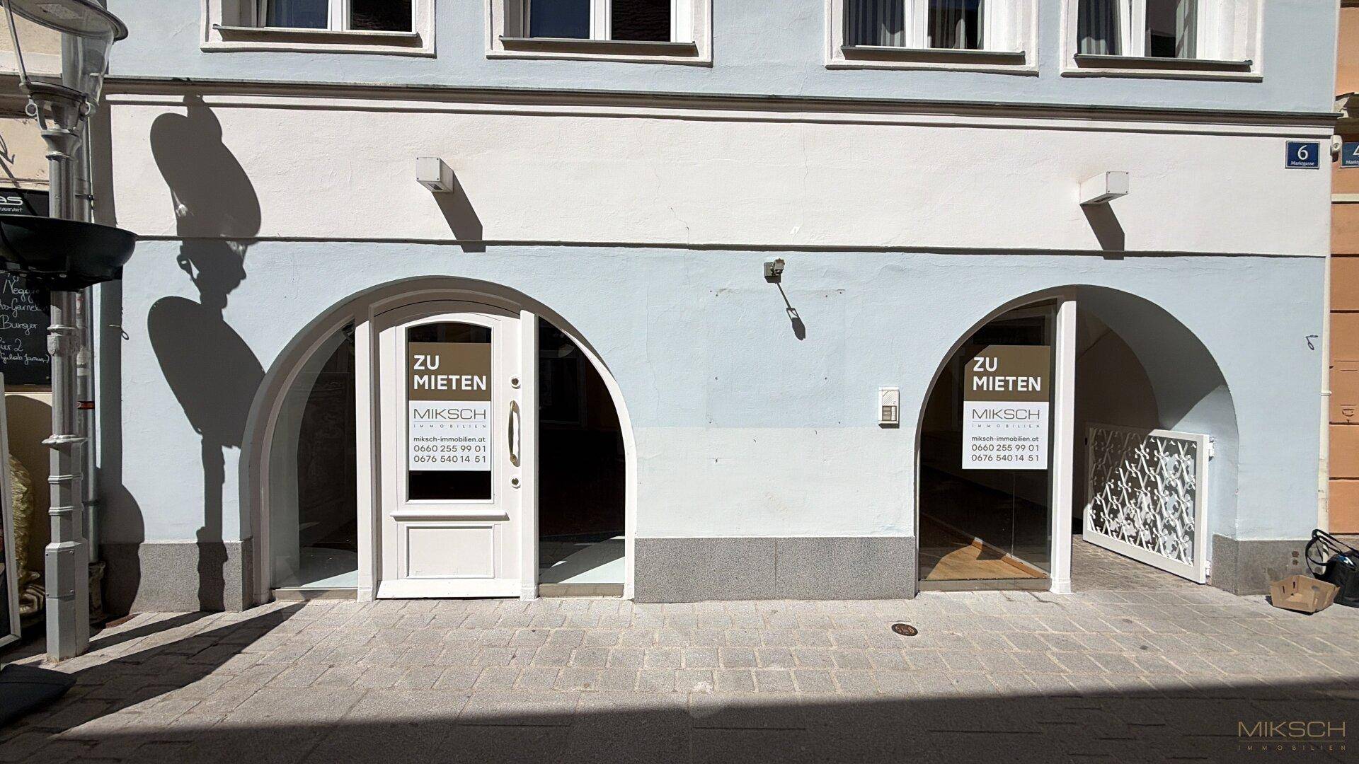 Fassade eines Gebäudes mit zwei gewölbten Eingängen und "Zu vermieten"-Schildern im Erdgeschoss.