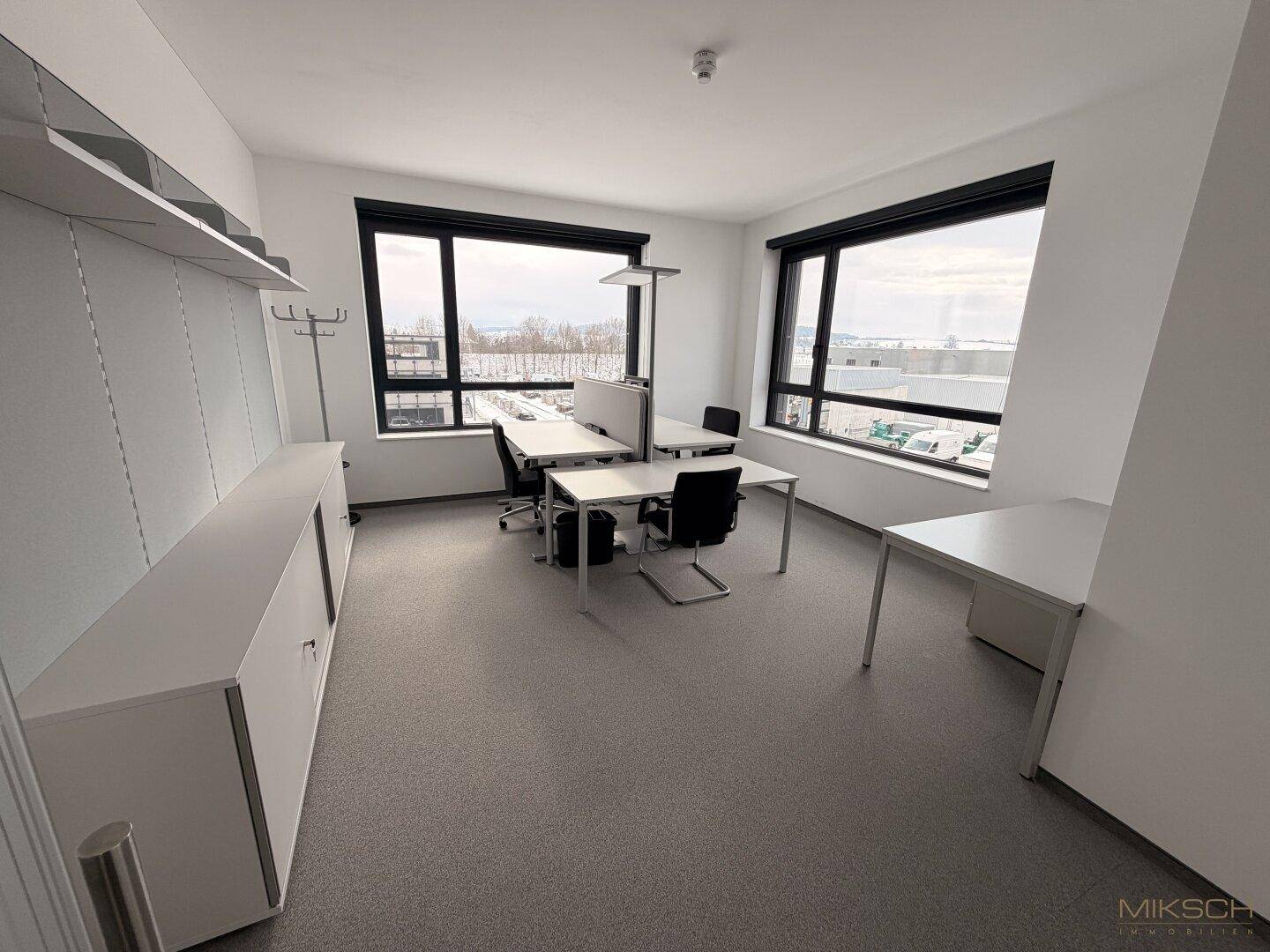 Großes Eckbüro mit mehreren Arbeitsplätzen, viel Tageslicht durch große Fenster und Blick ins Freie.