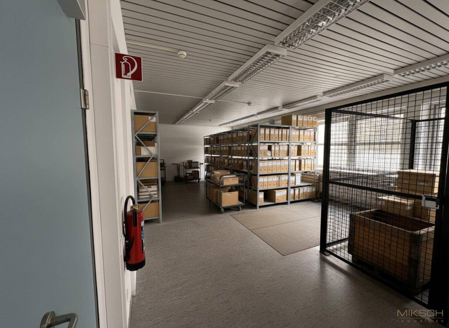 Lagerraum mit Regalen voller Kartons und einem Metallkäfig, ideal für die Archivierung oder Materiallagerung.