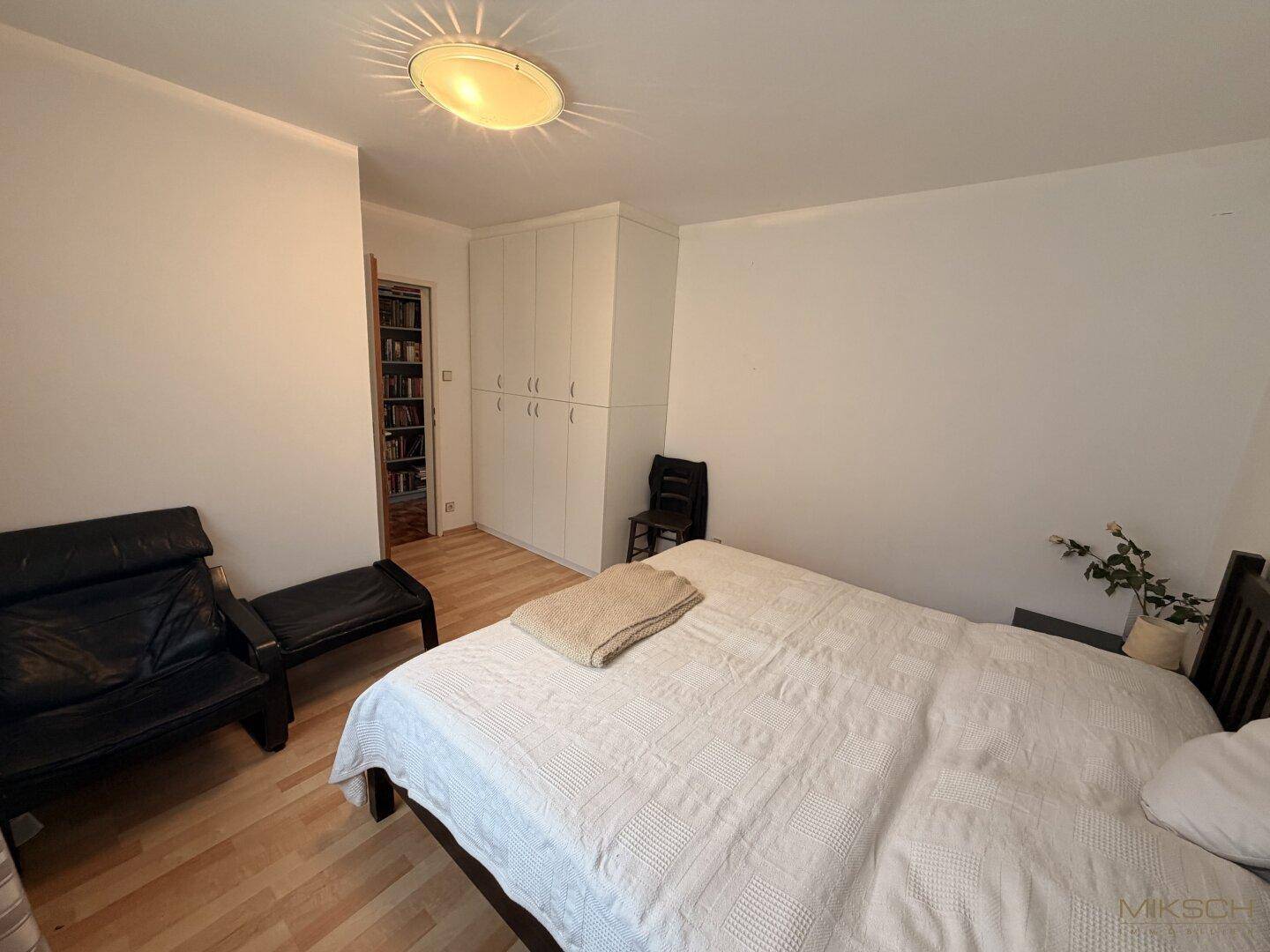 Gemütliches Schlafzimmer mit Doppelbett, Einbauschränken und hellem Holzboden.