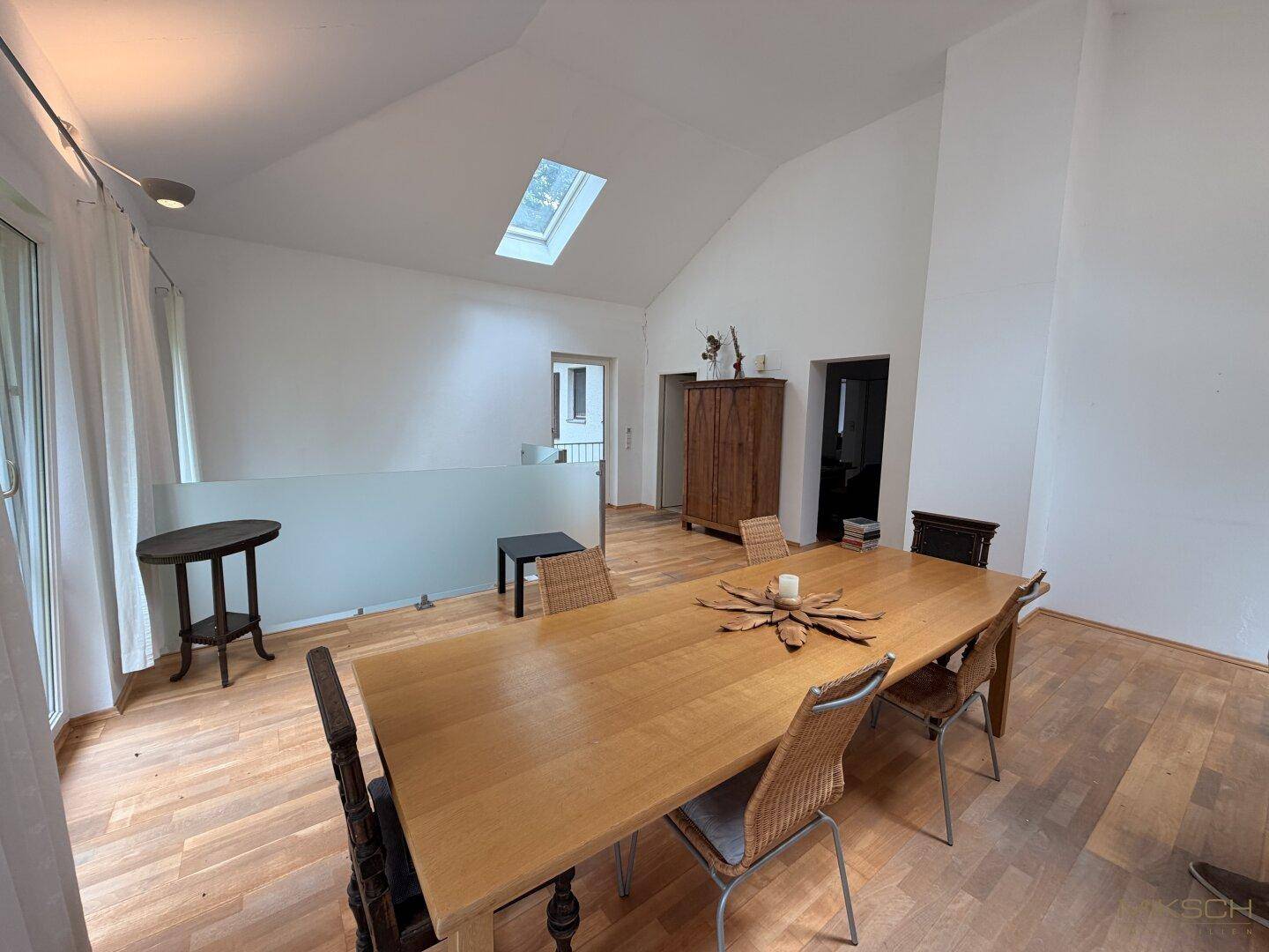 Geräumiger Essbereich mit Holzboden, hoher Decke und einem Dachfenster, das viel Licht spendet.