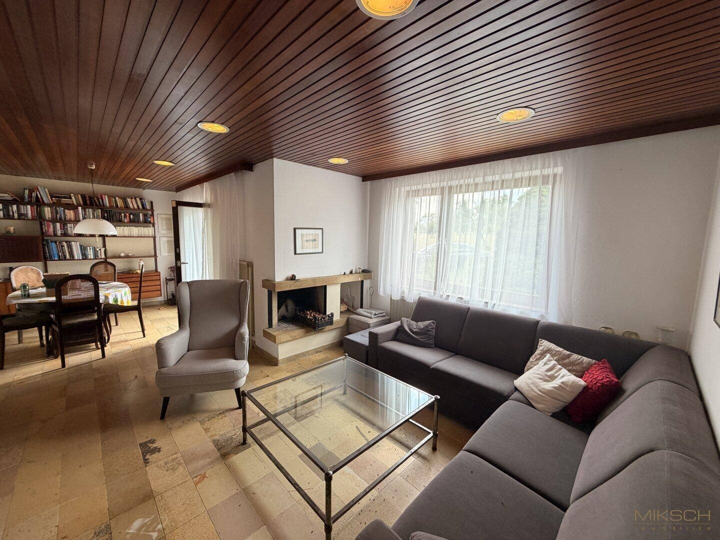 Gemütliches Wohnzimmer mit Kamin, großem Sofa und Holztäfelung an der Decke, ideal zum Entspannen.