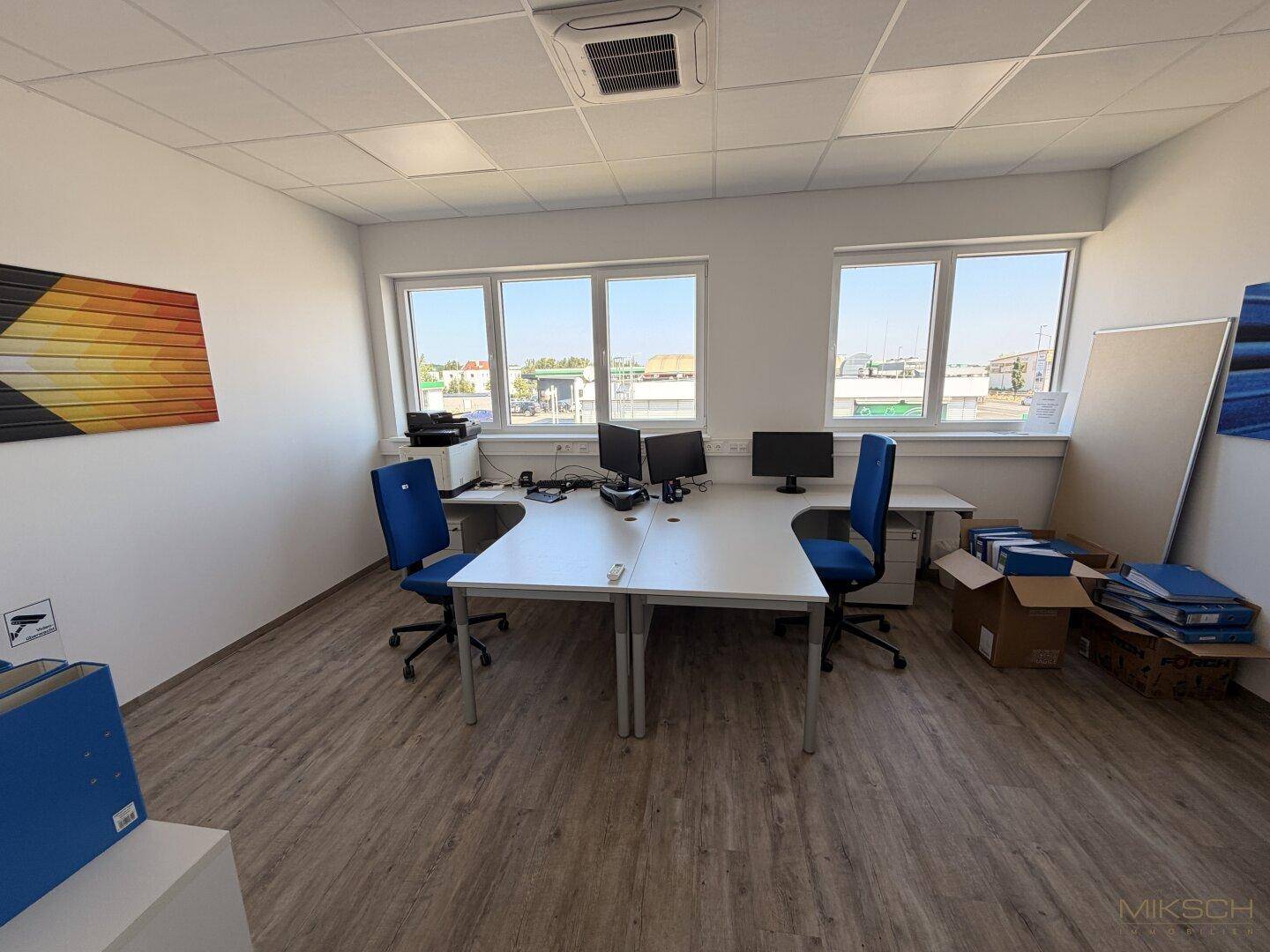 Modernes Büro mit zwei Arbeitsplätzen, Computern und Klimaanlage an der Decke.