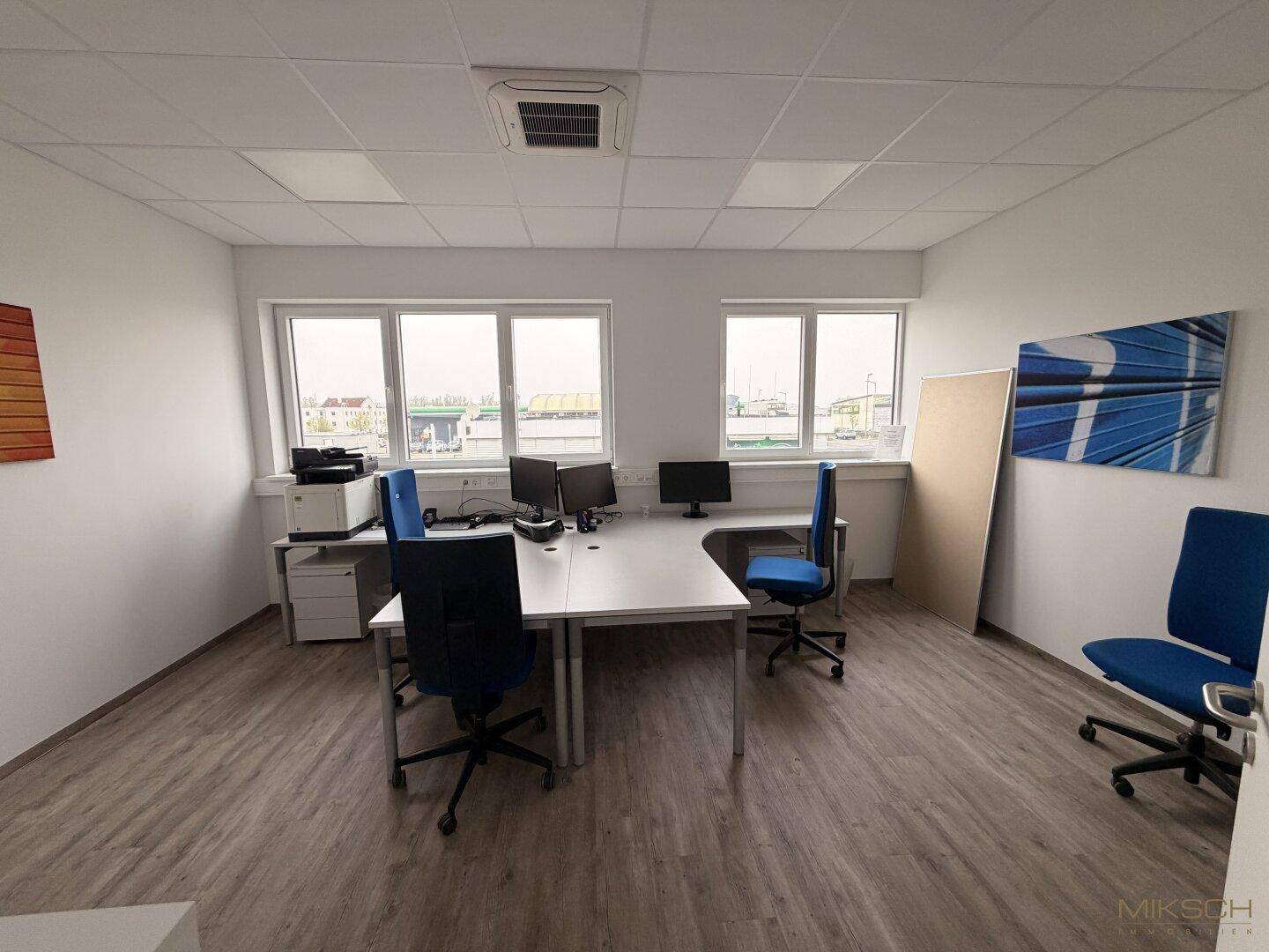 Geräumiges Büro mit zwei Arbeitsplätzen, Computern und Blick auf das Außengelände.