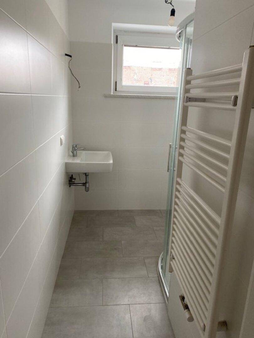 Modernes Badezimmer mit Dusche, Waschbecken, Fenster und beheiztem Handtuchhalter.