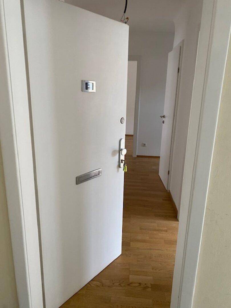 Eingangstür mit Sicherheitsschloss und Blick in den hellen Flur mit Holzboden.