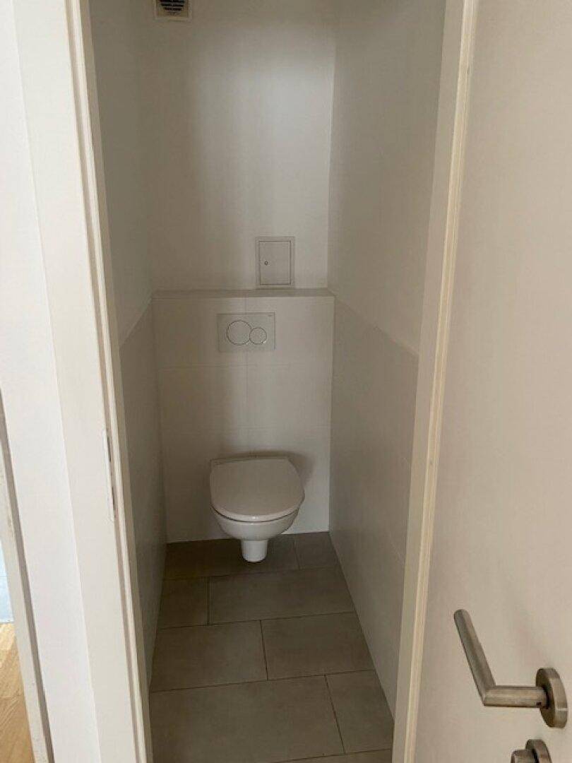 Kleines, funktionales WC mit Wand-WC und Fliesenboden in neutralen Farben.