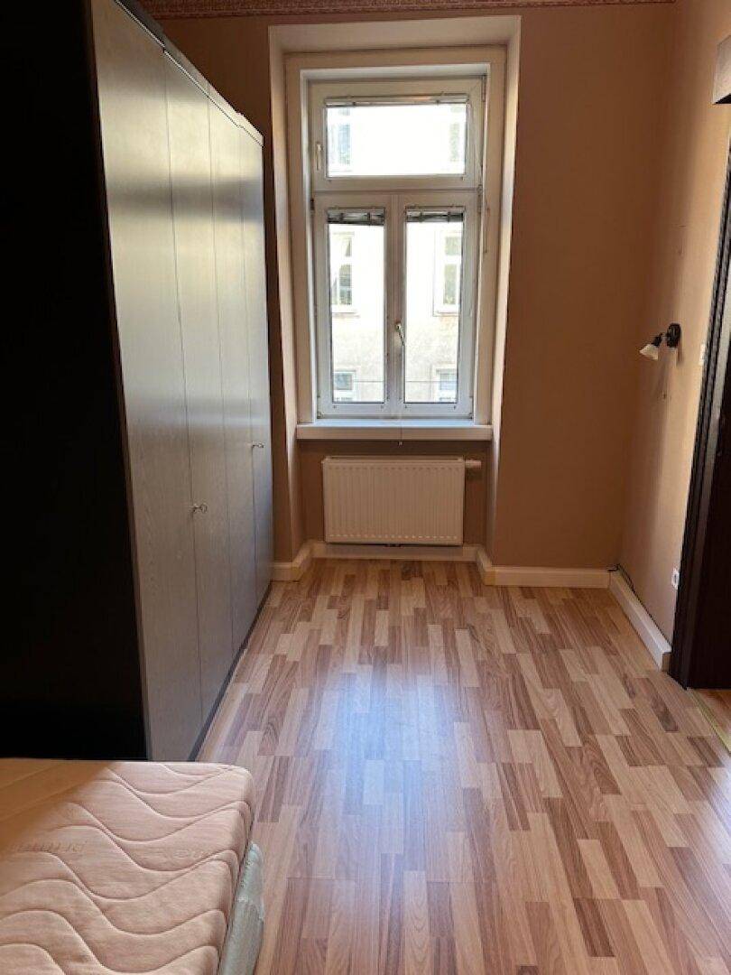 Schlafzimmer mit Laminatboden, Kleiderschrank und Fenster, bietet viel Tageslicht.