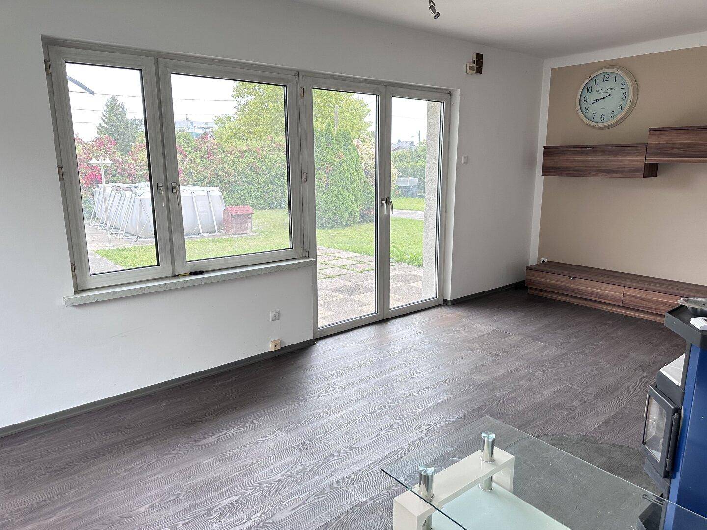 Geräumiges Wohnzimmer mit großen Fenstern, die viel Licht hereinlassen und Zugang zum Garten bieten.
