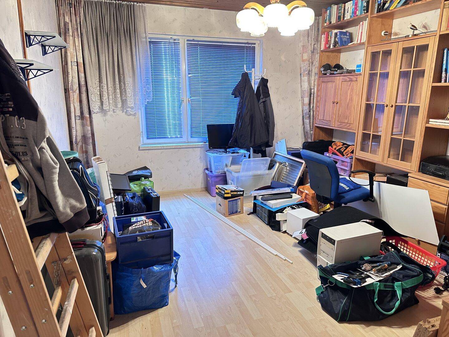 Schlafzimmer mit Holzpaneelen und Laminatboden, derzeit als Abstellraum genutzt.