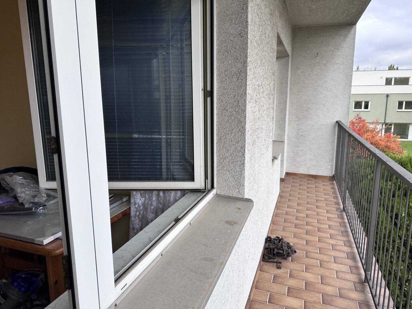 Seitliche Ansicht eines Balkons mit Fliesenboden und robustem Metallgeländer.